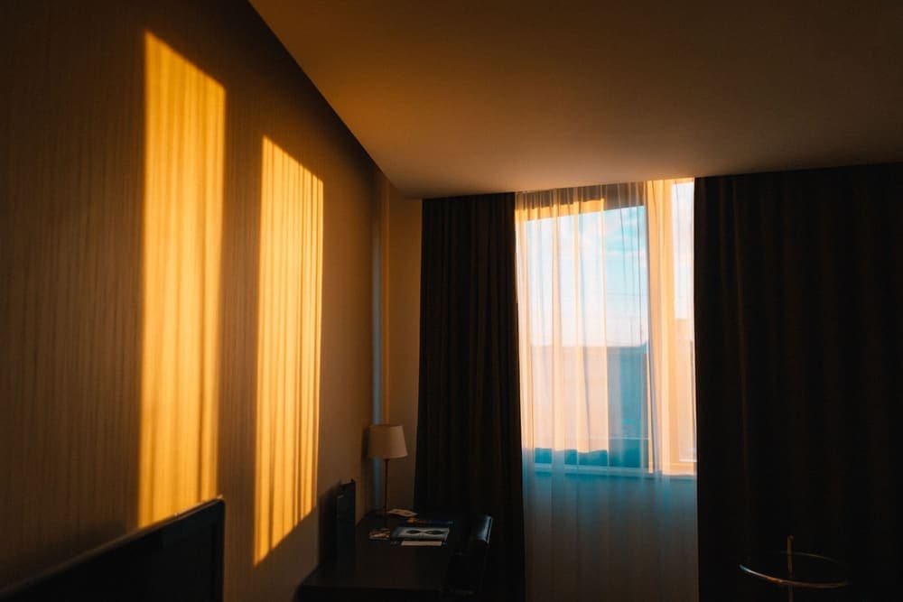 Morning light falling across a bedroom beside curtained windows