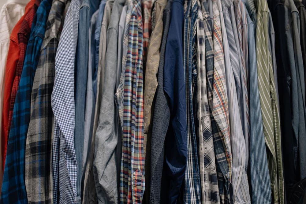 A closely packed row of shirts on a hanging rail