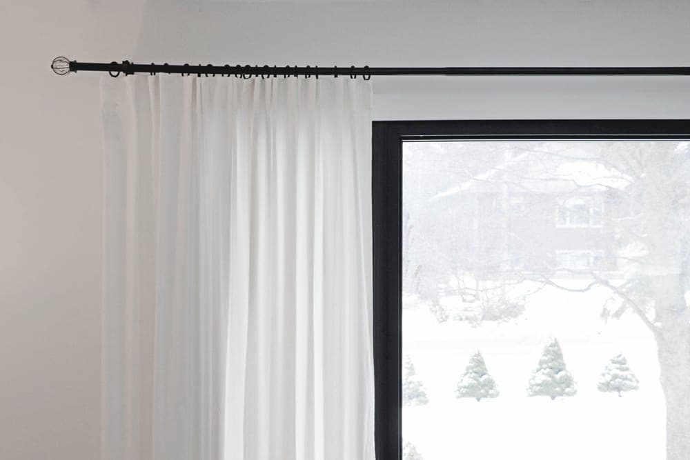 A curtain rod bracket at the corner of a window frame
