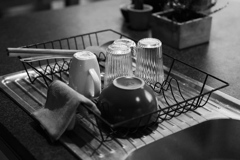 Glasses and ceramic dishes draining on a dish rack