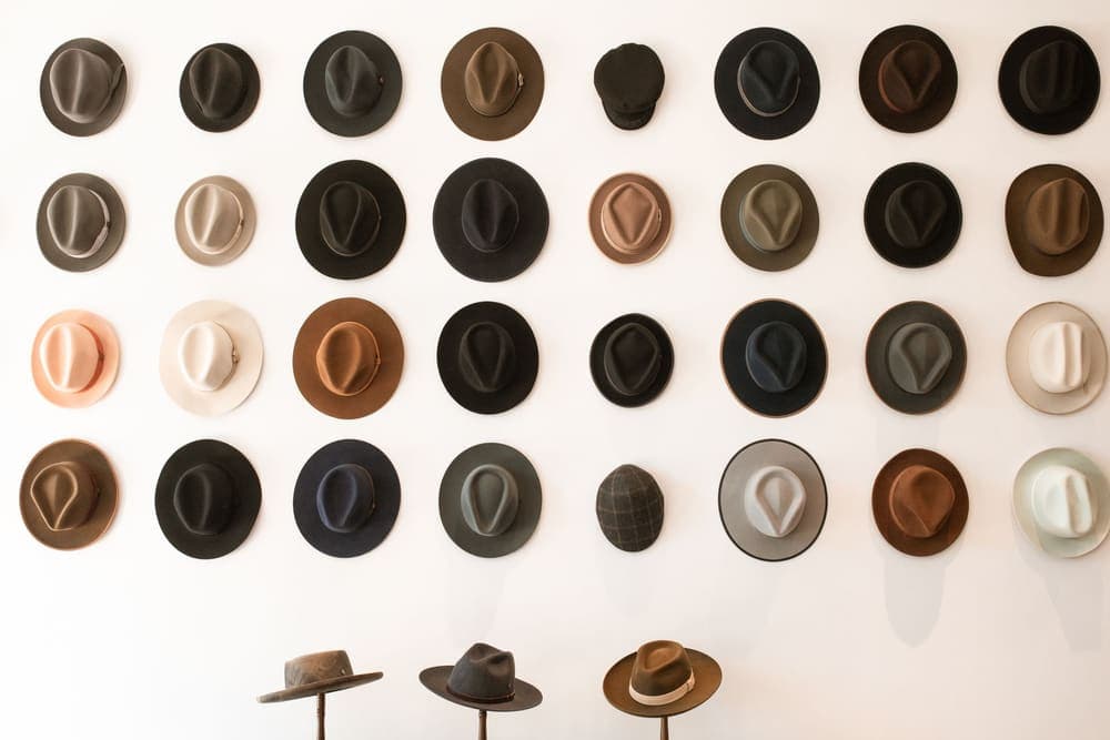 Hats arranged in a grid on a plain white wall