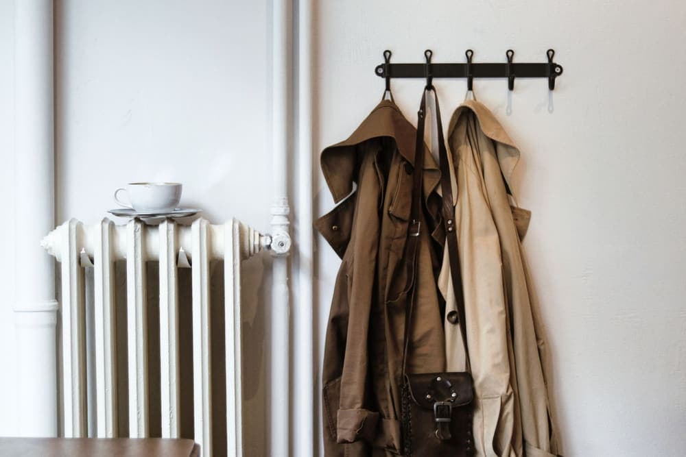 Coats and a shoulder bag hanging from hooks in a hallway
