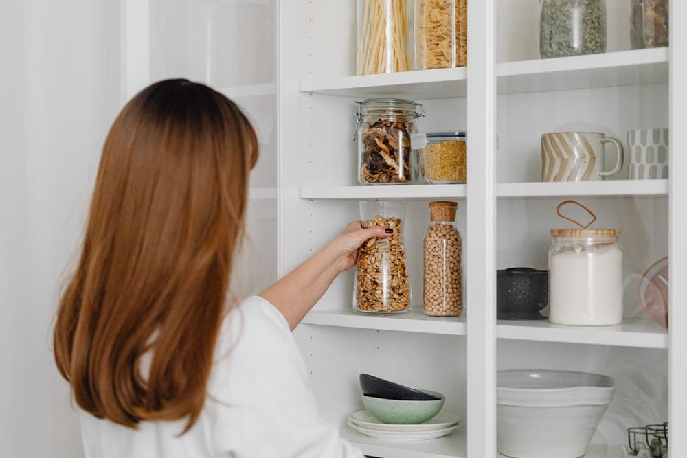 An organized kitchen cabinet with jars