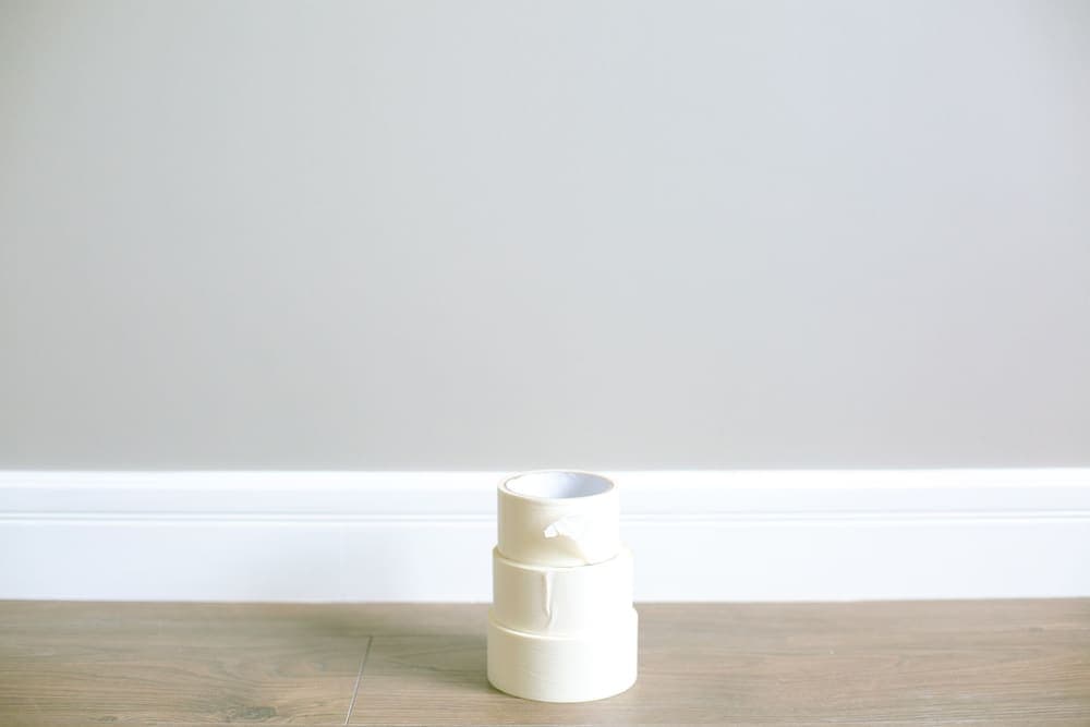 Rolls of tape stacked on the floor against a plain interior wall