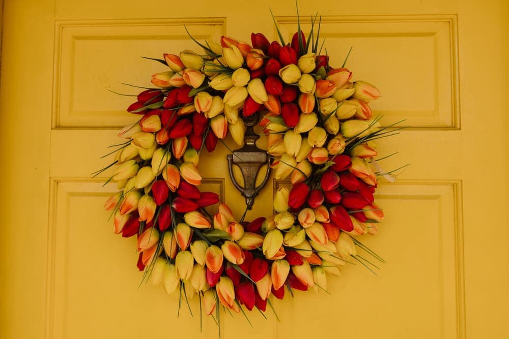 A tulip wreath hanging on a yellow front door
