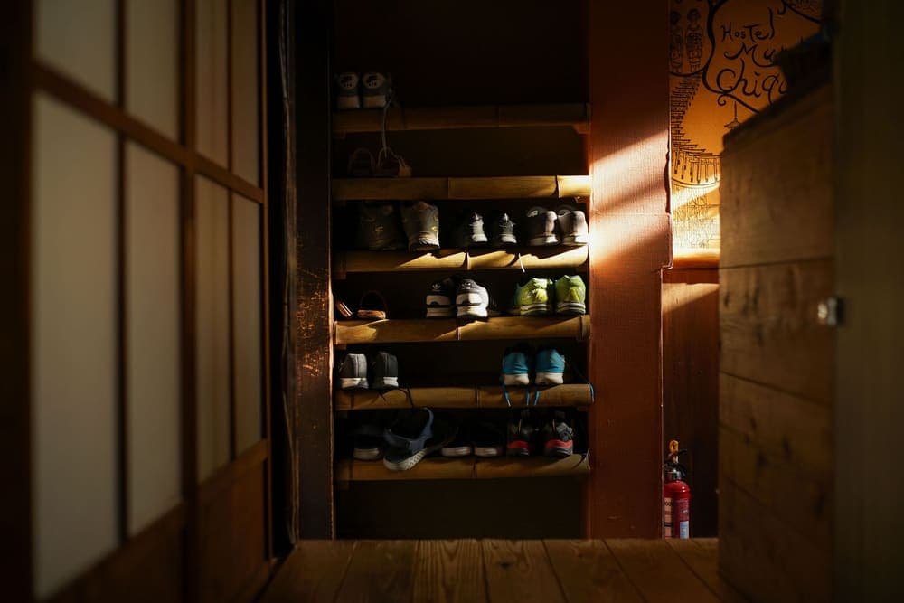 Sneakers arranged on a wooden shoe rack in a warmly lit entryway