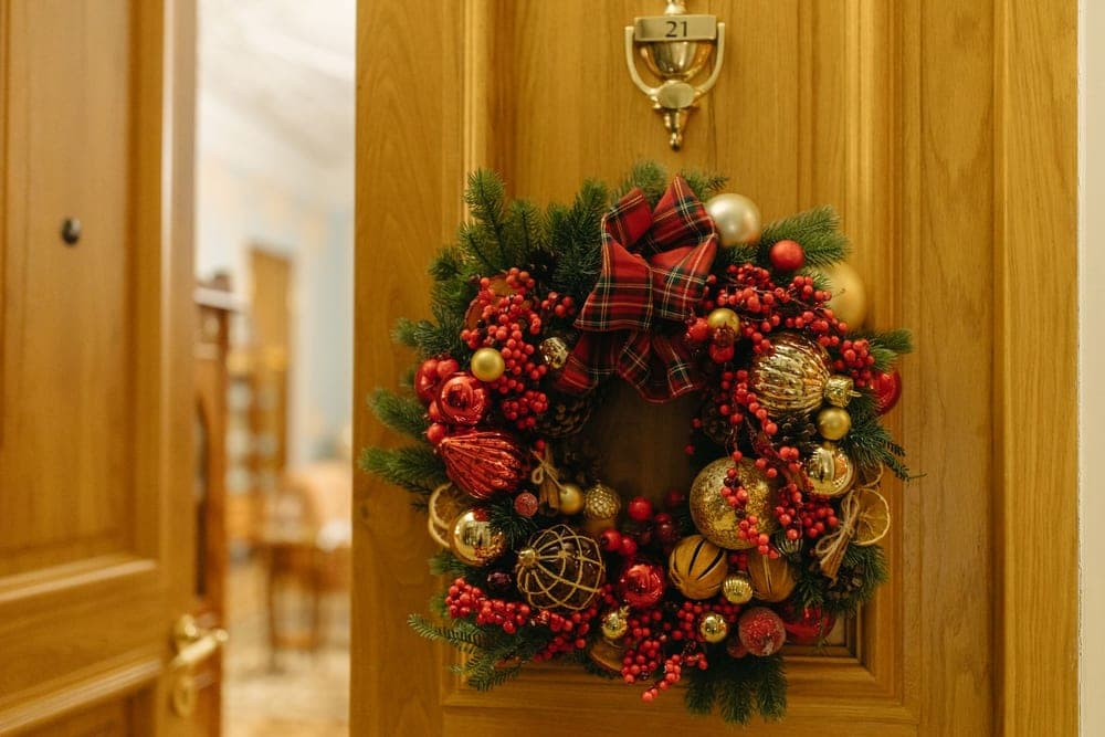 A decorated wreath hanging on the face of a wooden front door